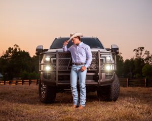 High school senior photoshoot in a field with a big truck in Livingston family ranch