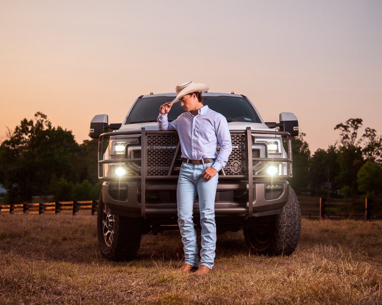 High school senior photoshoot in a field with a big truck in Livingston family ranch